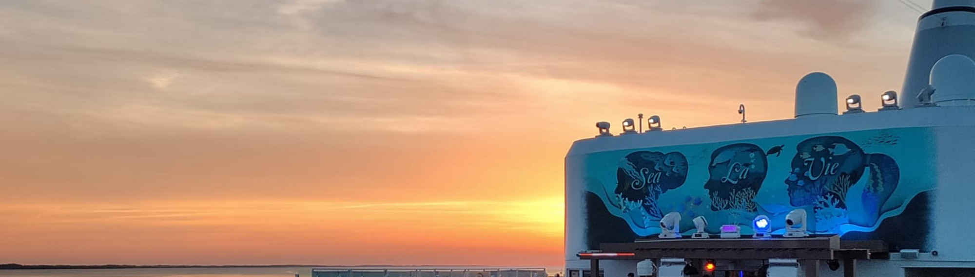Sonnenuntergang im Hintergrund. Das Agora Deck der Mein Schiff relax im Vordergrund